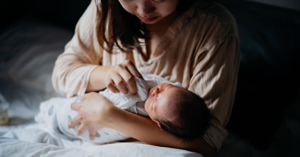 mother with newborn baby wiping mouth